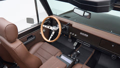 Interior of Classic Ford Bronco showing brown seats, wooden steering wheel, and dashboard