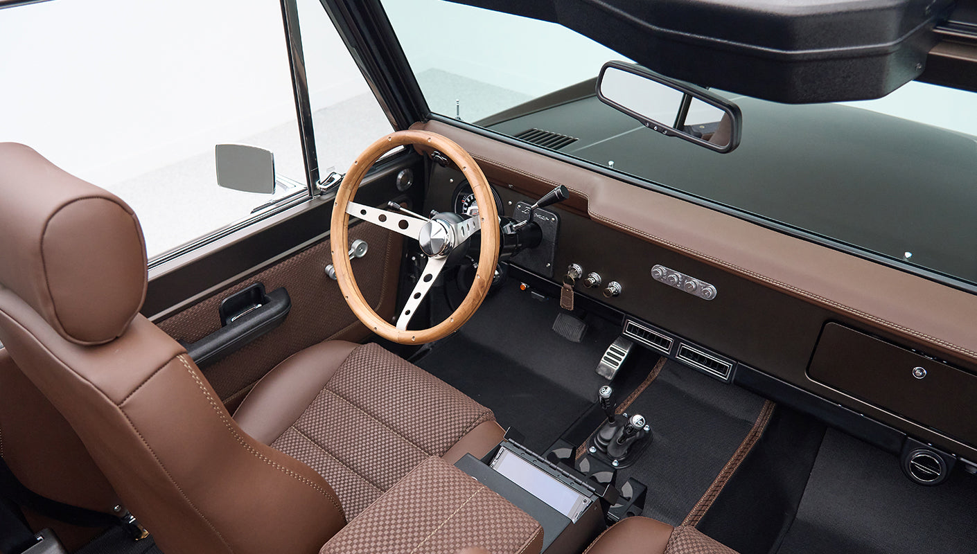 Interior of Classic Ford Bronco showing brown seats, wooden steering wheel, and dashboard