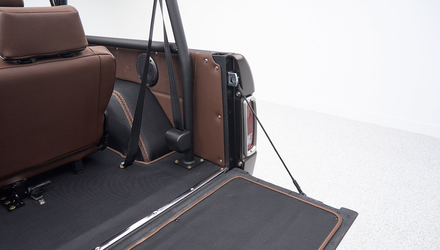 Rear section inside a Classic Ford Bronco with brown leather and seat belt attached to roll cage