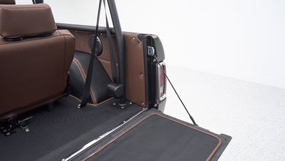 Rear section inside a Classic Ford Bronco with brown leather and seat belt attached to roll cage