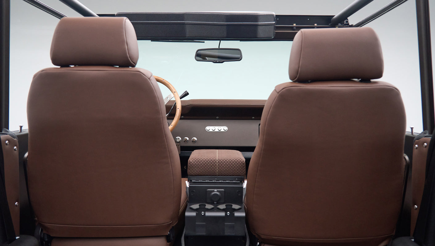 Front seats and dashboard view from rear of Classic Ford Bronco with brown leather seats