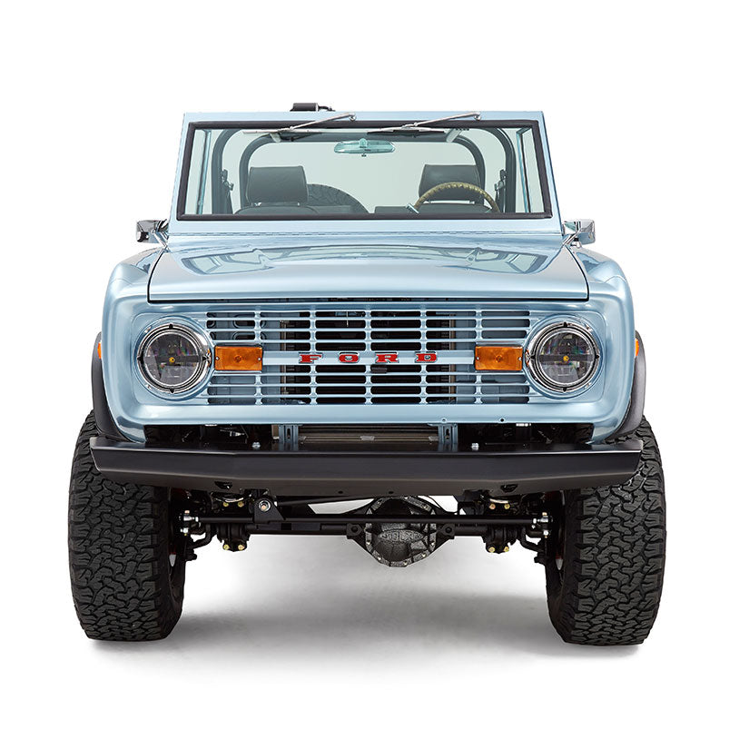 Front view of light blue Classic Ford Bronco with large off-road tires and windshield