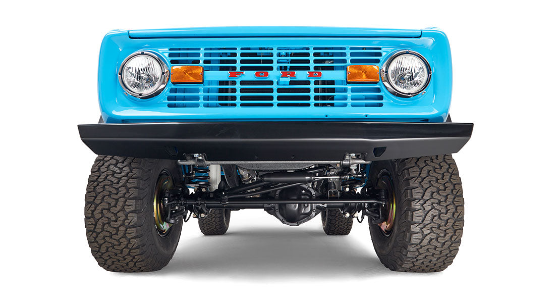 Front underside view of a bright blue Classic Ford Bronco with visible suspension and tires