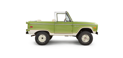 Side view of green Classic Ford Bronco with beige seats and no roof