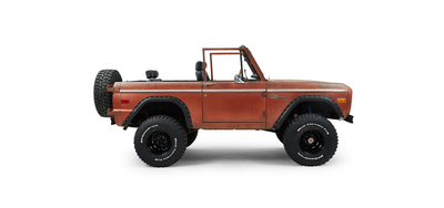 Passenger side view of a red Classic Ford Bronco with black wheel arches and spare tire on back