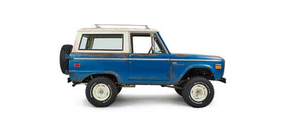 Classic Ford Bronco passenger side view with white roof and mounted spare tire