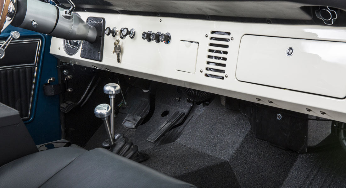 Interior floor area of a Classic Ford Bronco showing pedals, shifters, and part of dashboard