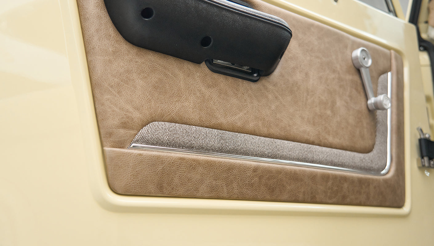 Close-up of Classic Ford Bronco driver door panel with beige leather and fabric upholstery