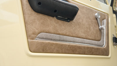 Close-up of Classic Ford Bronco driver door panel with beige leather and fabric upholstery