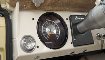 Classic Ford Bronco dashboard featuring round speedometer and black panel with Bronco emblem