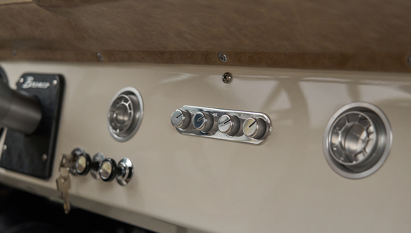Close view of Classic Ford Bronco dashboard controls and round air vents in beige interior