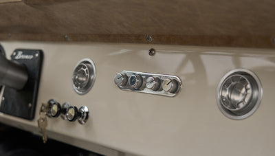 Close view of Classic Ford Bronco dashboard controls and round air vents in beige interior