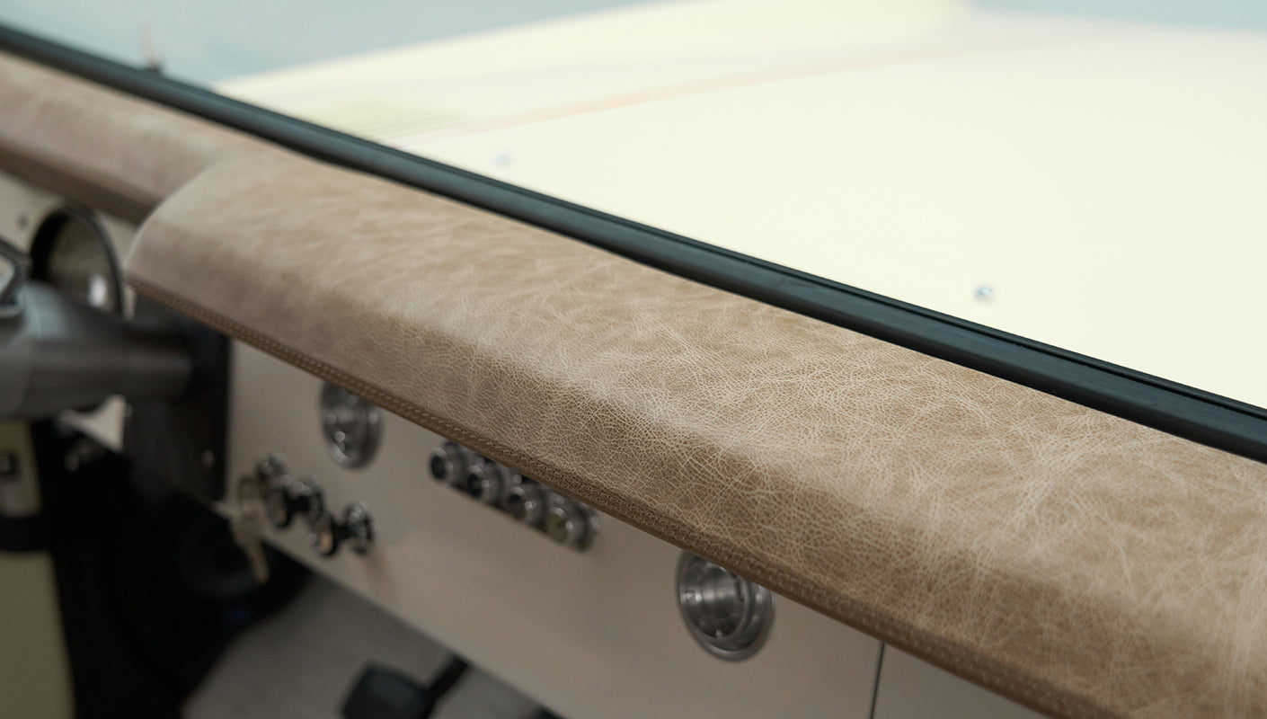 Beige leather dashboard padding of Classic Ford Bronco above control panel and air vents