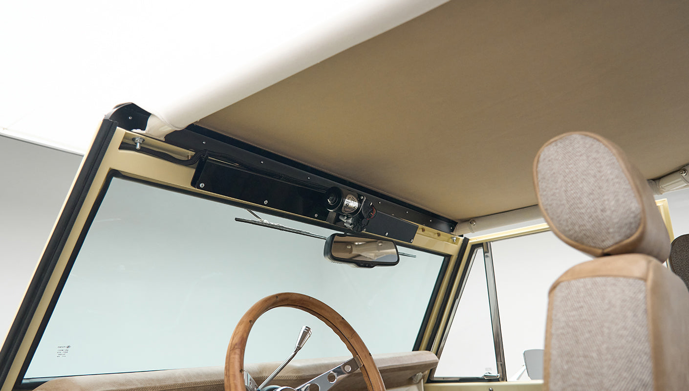 Inside view of Classic Ford Bronco showing windshield, rear-view mirror, and steering wheel with wood grains