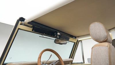 Inside view of Classic Ford Bronco showing windshield, rear-view mirror, and steering wheel with wood grains