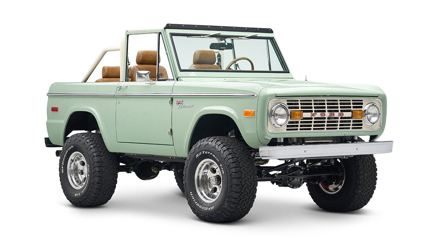 Front view of green Classic Ford Bronco convertible with chrome wheels and off-road tires