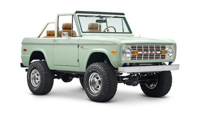 Front view of green Classic Ford Bronco convertible with chrome wheels and off-road tires