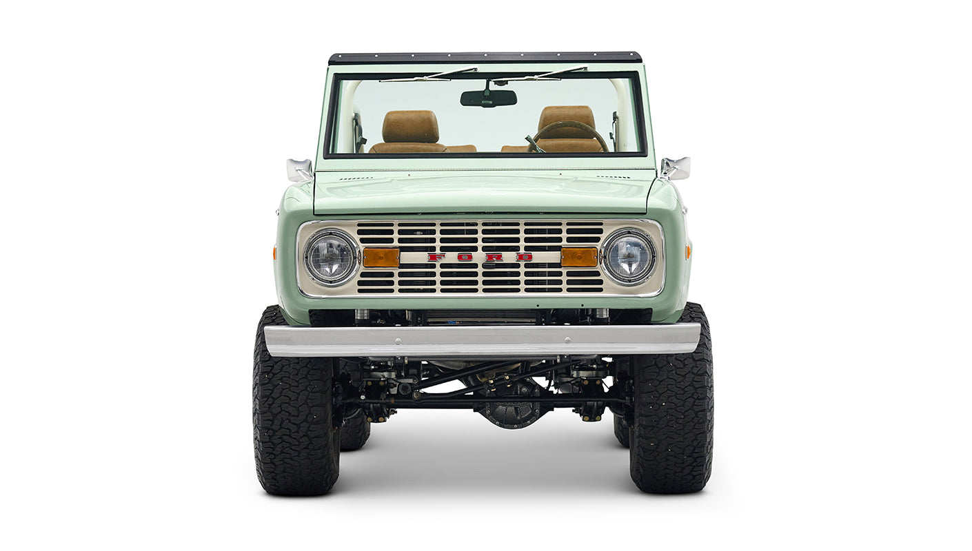 Front view of porcelain green Classic Ford Bronco showing grill, headlights, and lifted suspension