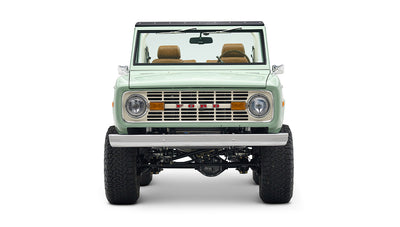 Front view of porcelain green Classic Ford Bronco showing grill, headlights, and lifted suspension
