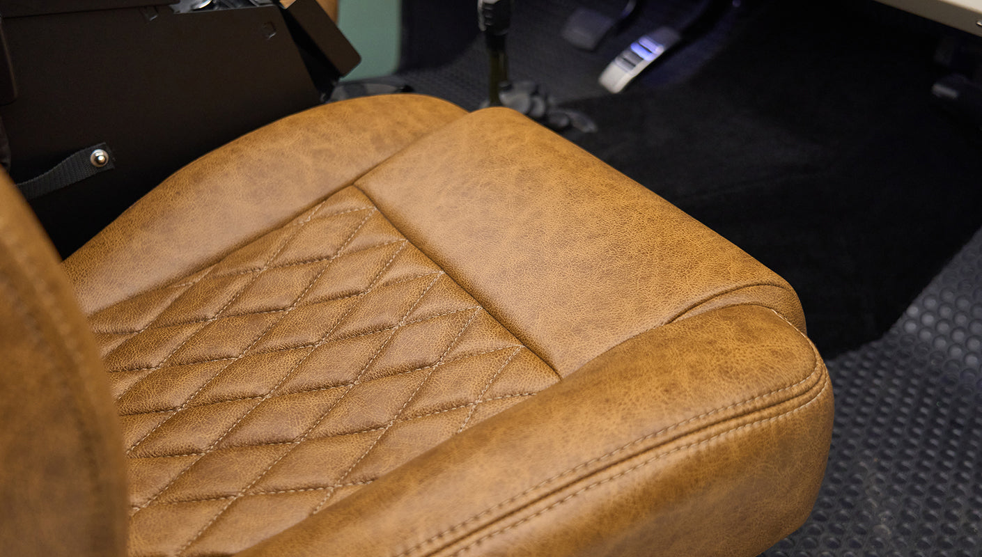 Close-up of driver's seat in Classic Ford Bronco showing brown leather upholstery with diamond pattern