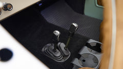 Classic Ford Bronco interior showing two gear shift levers on black carpet floor