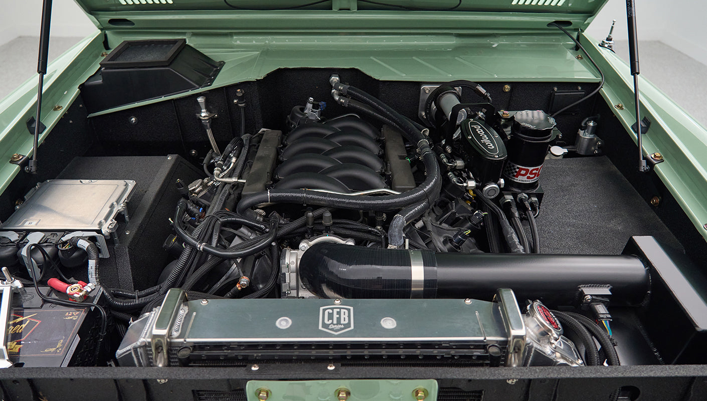 Close-up of Classic Ford Bronco engine compartment with green edges and multiple hoses