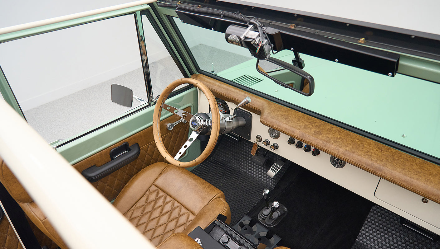 Classic Ford Bronco interior with tan leather seats, steering wheel and dashboard visible