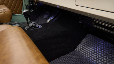 Floor area of Classic Ford Bronco showing black carpet and rubber floor mats near gear levers
