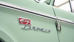 Close-up of Classic Ford Bronco badge on porcelain green hood with side marker light