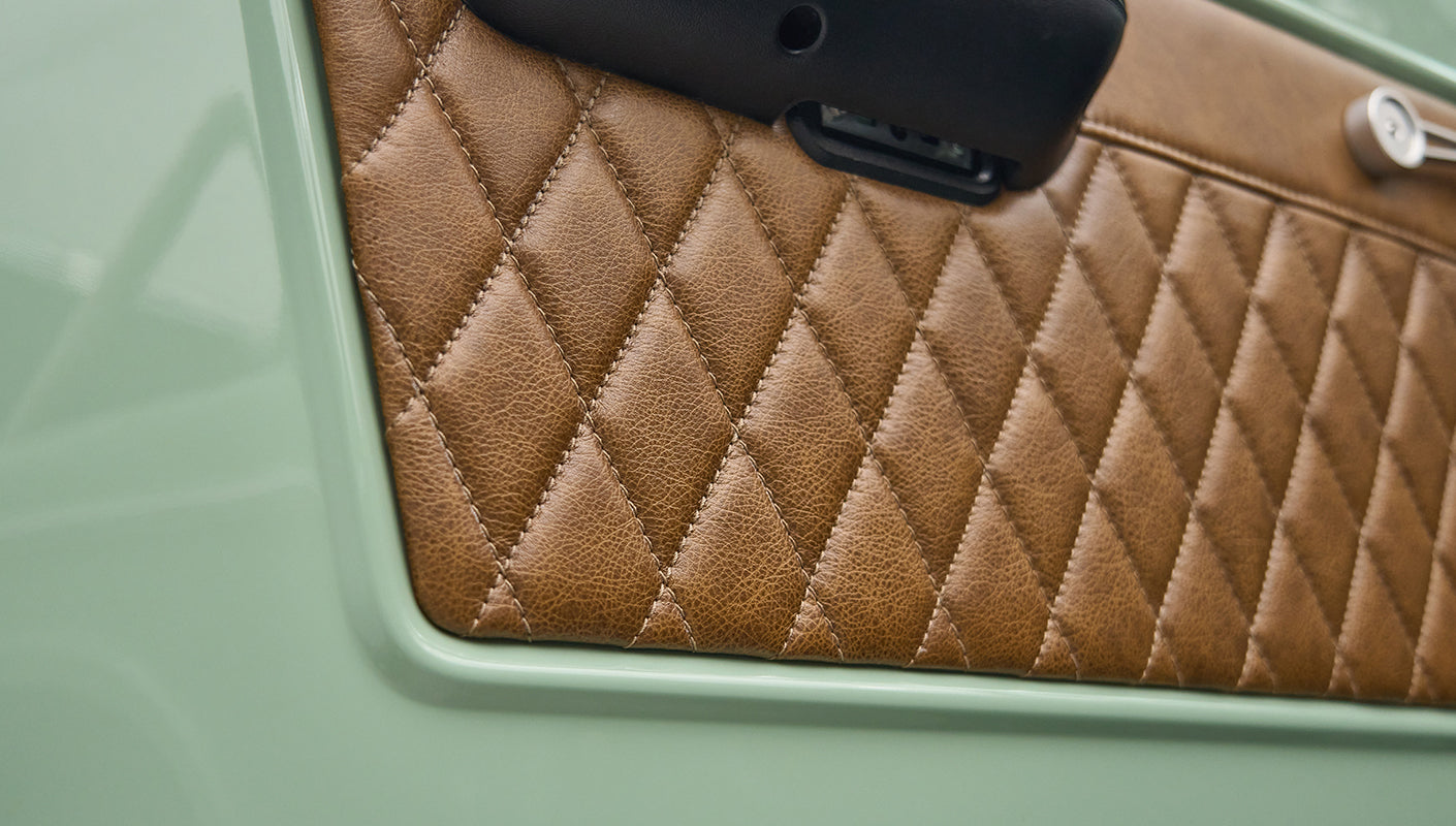 Close-up of brown diamond-stitched leather interior panel on green door