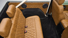 Rear passenger seat and black carpet floor inside Classic Ford Bronco with brown leather seats