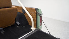 Rear interior corner of Classic Ford Bronco showing brown diamond-stitched panel and white roll bar