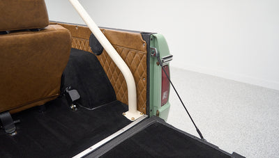 Rear interior corner of Classic Ford Bronco showing brown diamond-stitched panel and white roll bar