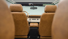 Rear view of brown leather front seats and dashboard with steering wheel in Classic Ford Bronco