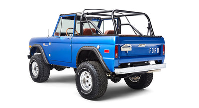 Rear angled view of blue Classic Ford Bronco showing driver-side and large off-road tires