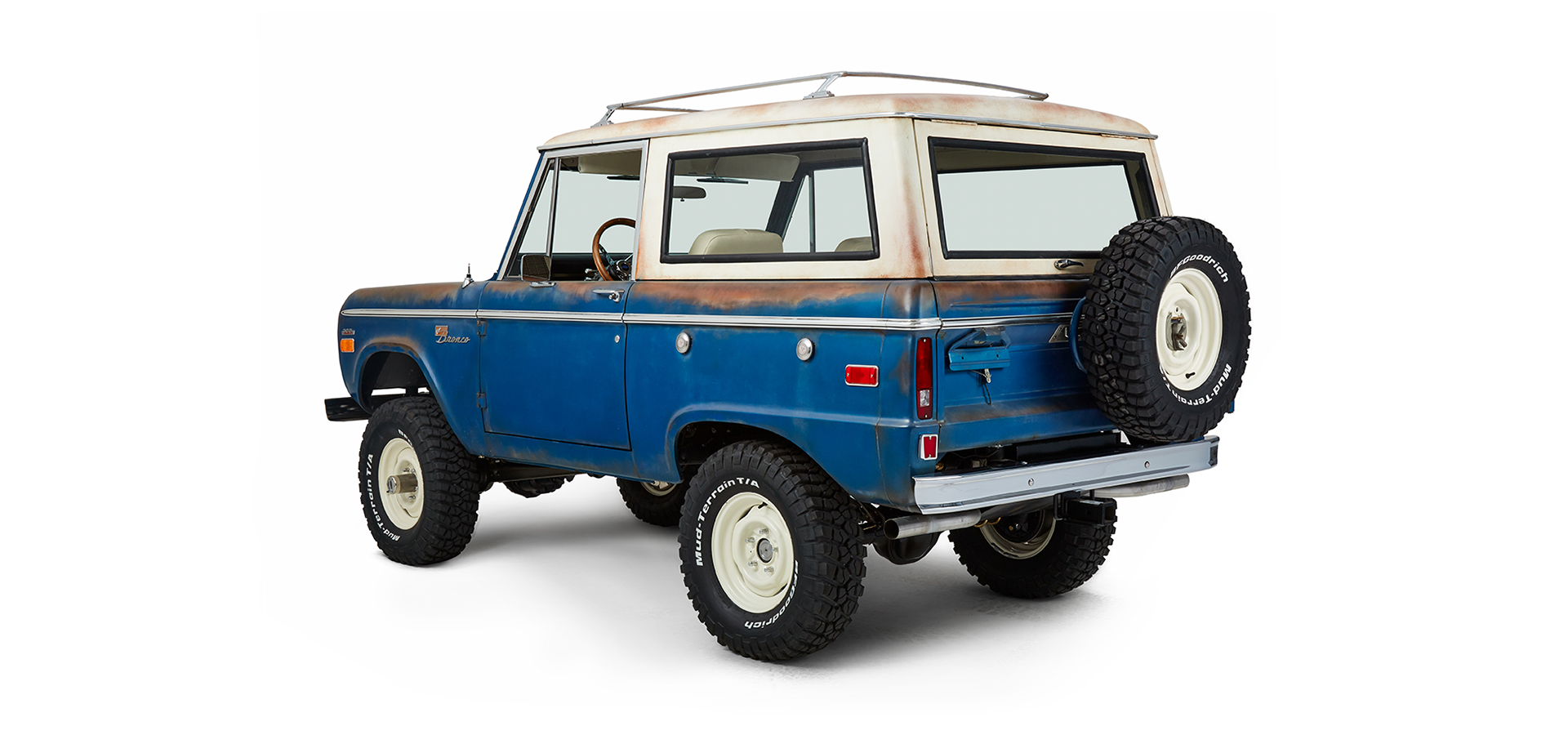Classic Ford Bronco rear driver side angled view showing spare tire, taillights, and bumper