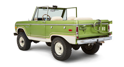Rear driver angle of green Classic Ford Bronco showing spare tire mount and open roof