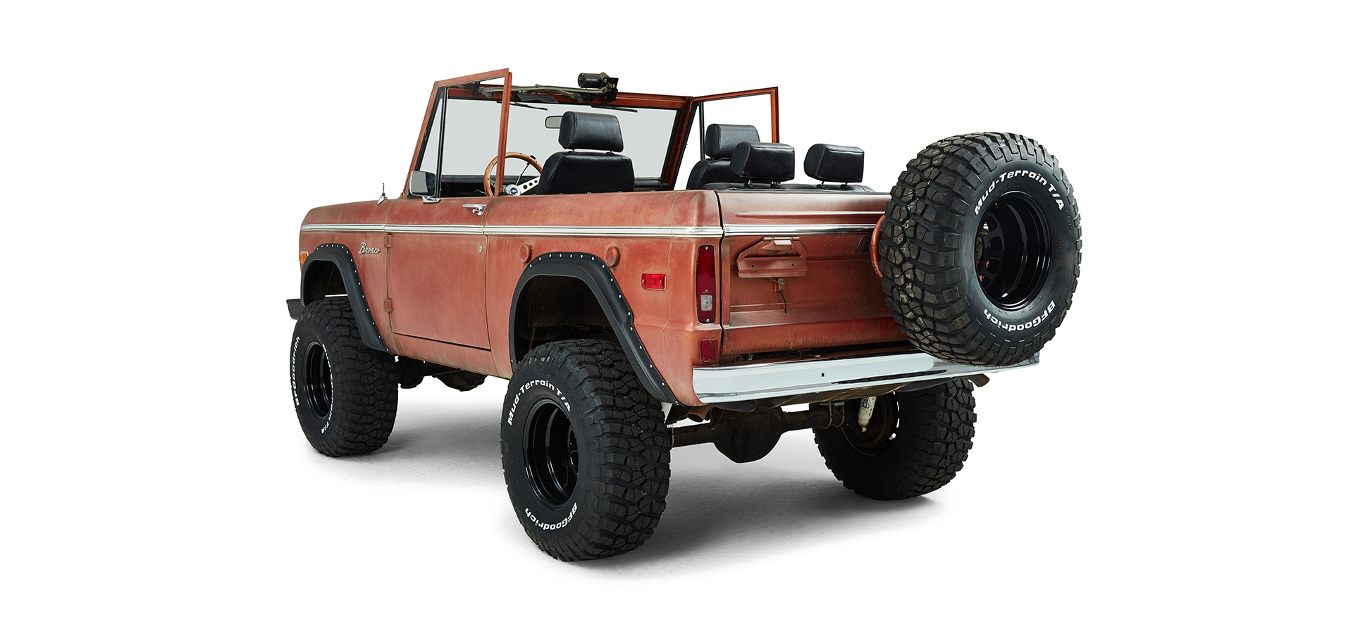 Rear driver angle view of a red Classic Ford Bronco with doors open and black fender flares