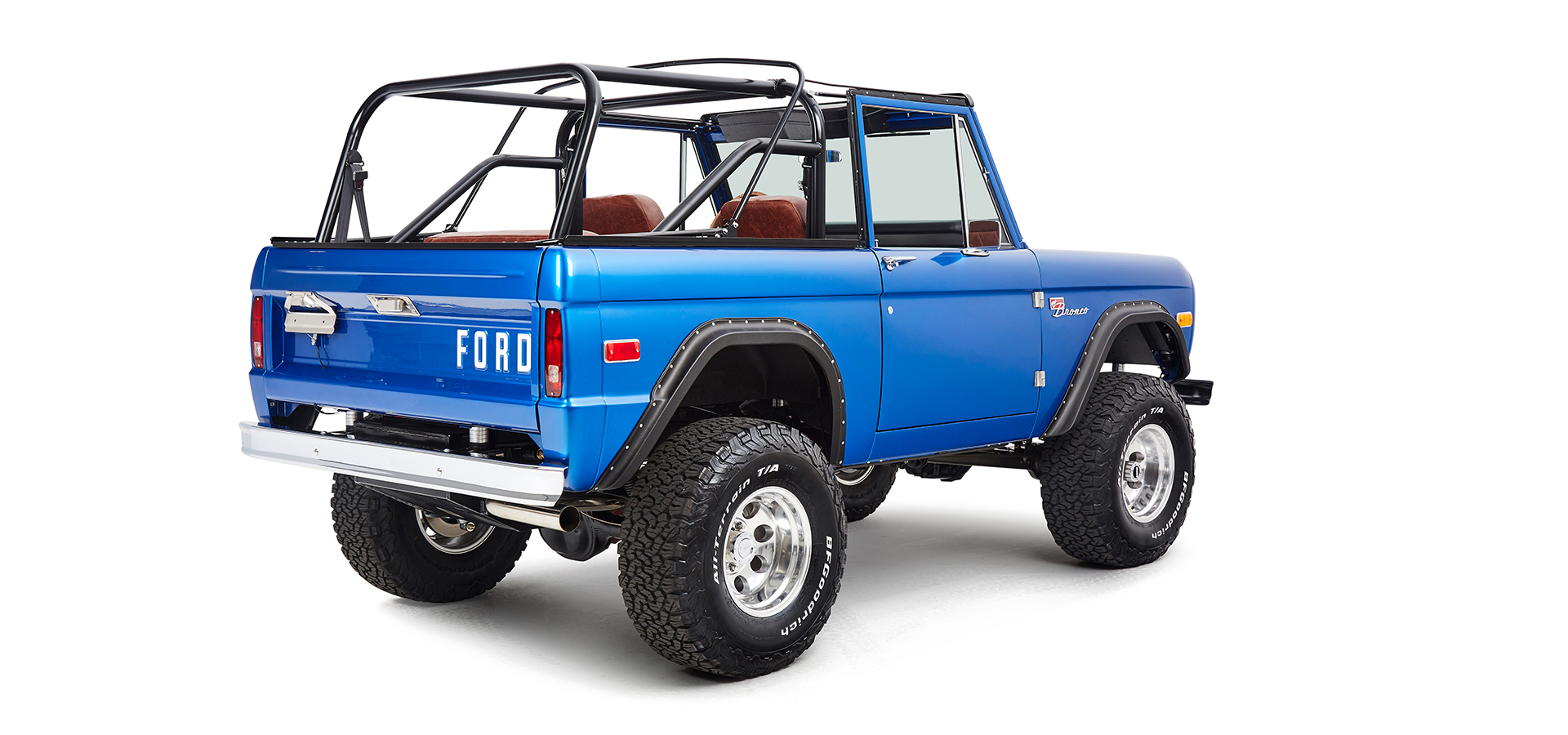 Blue Classic Ford Bronco rear passenger angled view showing rear tailgate and large tires