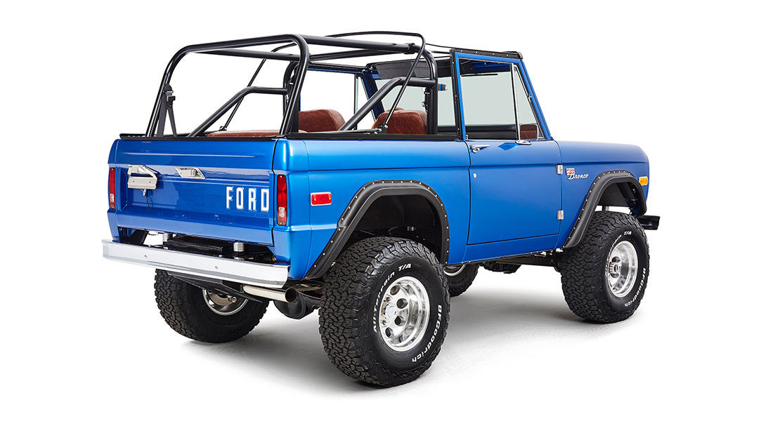 Rear angled view of blue Classic Ford Bronco showing passenger-side and off-road tires