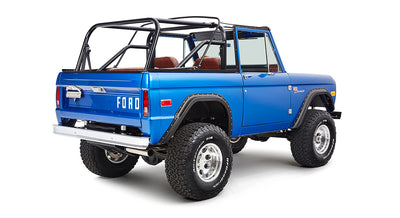 Rear angled view of blue Classic Ford Bronco showing passenger-side and off-road tires