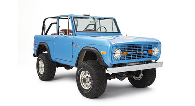 Three-quarter front view of sky blue Classic Ford Bronco with open roof and off-road tires