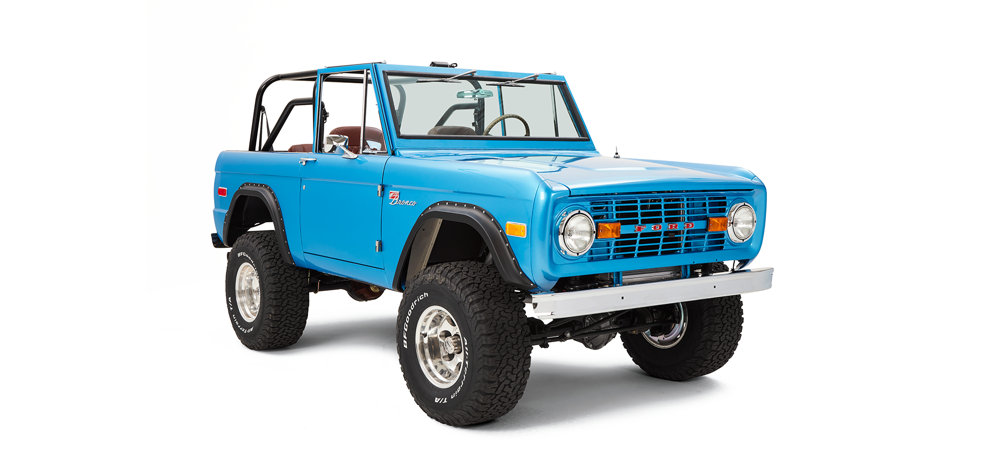 Three-quarter front view of sky blue Classic Ford Bronco with roll cage and large off-road tires