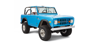 Three-quarter front view of sky blue Classic Ford Bronco with roll cage and large off-road tires