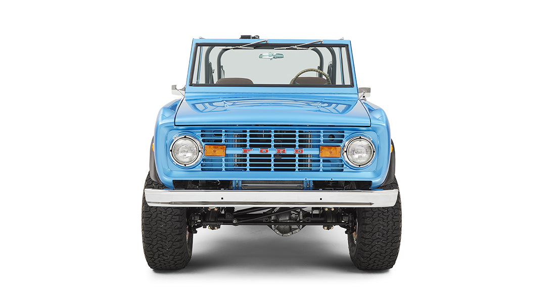 Sky blue Classic Ford Bronco seen from front with windshield, grille, headlights, and raised tires