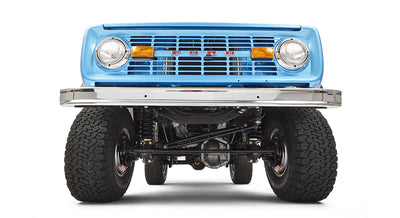 Front close-up showing sky blue Classic Ford Bronco grille with headlights and large tires underneath