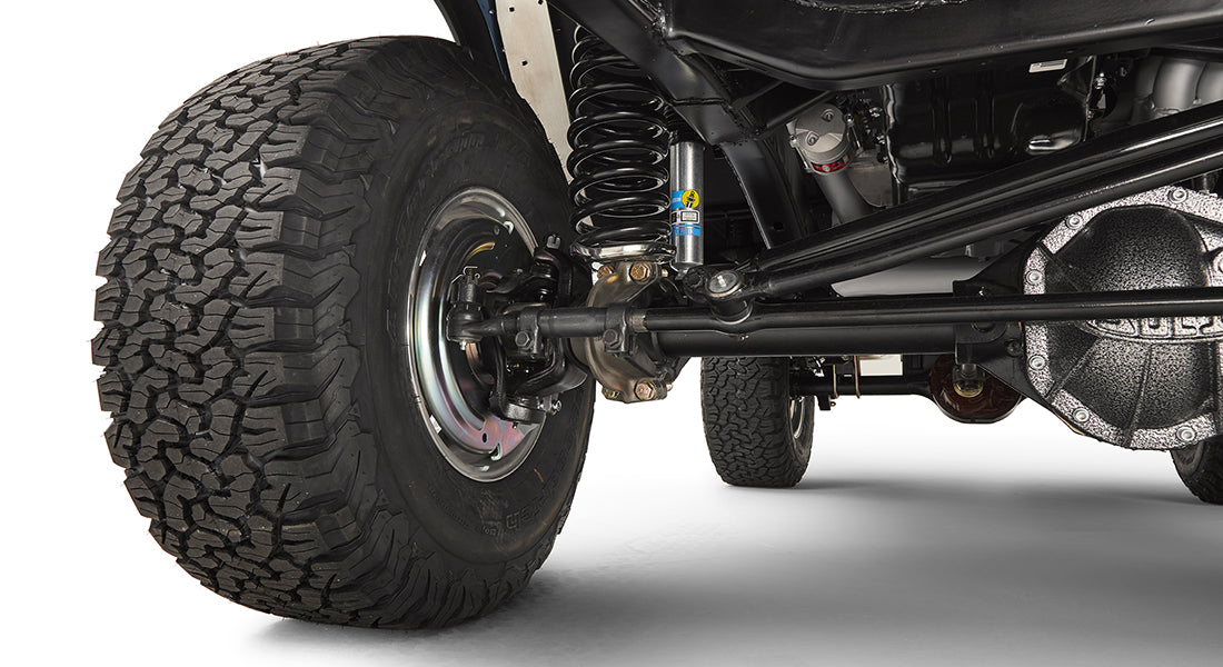 Close-up of front wheel, suspension, and steering linkage components under Classic Ford Bronco.