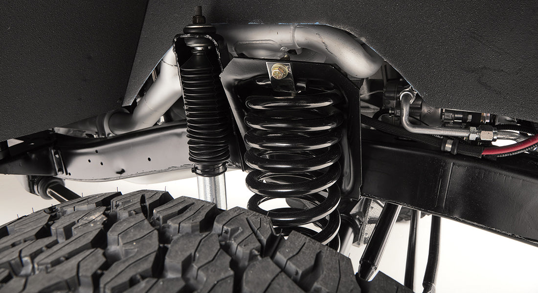 Close-up of suspension coil spring and shock absorber over off-road tire.