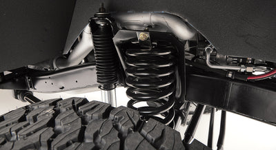 Close-up of suspension coil spring and shock absorber over off-road tire.