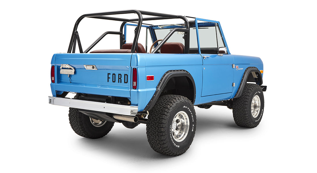 Rear three-quarter view of sky blue Classic Ford Bronco with roll cage and large off-road tires